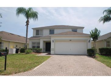 Charming two-story home with a brick driveway, well-manicured lawn and a palm tree at 257 Lancaster Dr, Davenport, FL 33897