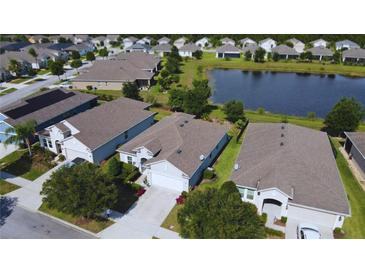 An aerial view of a neighborhood showcases the house, its well-maintained lawn, and a nearby pond, all under a bright, sunny sky at 3333 Sagebrush St, Harmony, FL 34773