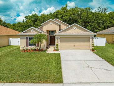 Charming single-story home featuring a well-manicured lawn, mature landscaping, and an attached two-car garage at 4726 Ashurst St, Kissimmee, FL 34758