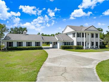 Stately two-story home features white columns, lush landscaping, and a long driveway at 5150 Gentry Oaks Pl, St Cloud, FL 34772
