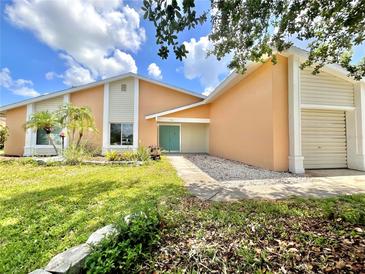 Inviting single-story home with lush landscaping, charming curb appeal, and a colorful front door at 713 Wood Ln, Kissimmee, FL 34759