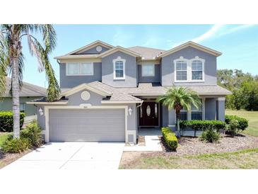 Charming two-story home with gray stucco, neutral trim, attached two-car garage, and well manicured landscaping at 805 Suffolk Pl, Davenport, FL 33896