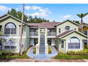 Charming two-story condo building featuring green paint, white trim, and beautiful landscaping, perfect for a serene living at 3151 Britannia Blvd # C, Kissimmee, FL 34747