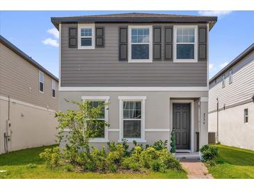 Charming two-story home featuring neutral gray siding, decorative shutters, and manicured front garden at 4736 Homestead Trl, St Cloud, FL 34772