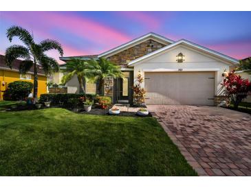 Charming single Gathering home featuring stone accents, paver driveway, a well-manicured lawn and lush landscaping at 582 San Joaquin Rd, Poinciana, FL 34759