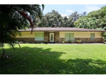 Charming single story home with a stone facade and a large, well-manicured front yard at 860 Oak Shore Dr, St Cloud, FL 34771