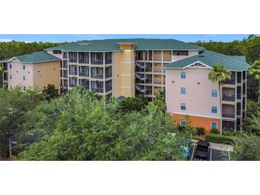 Three-story condo building with green roof surrounded by lush trees and landscaping at 9055 Treasure Trove Ln # 207, Kissimmee, FL 34747