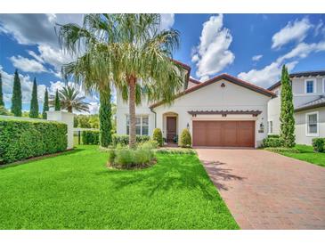 Charming home with a lush green lawn, a brick driveway, and a well-manicured landscape and a tropical palm tree at 10836 Royal Cypress Way, Orlando, FL 32836