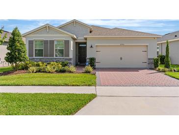 Charming single-story home with a well-manicured lawn, brick driveway, and neutral stucco exterior at 17795 Blazing Star Cir, Clermont, FL 34714