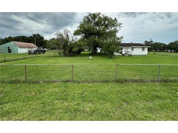 Spacious, grassy yard with a chainlink fence surrounds this single-Gathering home at 1886 Pleasant Hill Rd, Kissimmee, FL 34746