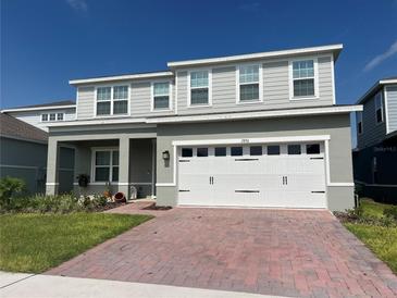 Charming two-story home features a brick driveway, neutral gray paint, and a two-car garage at 1896 Basenji Dr, Lake Alfred, FL 33850