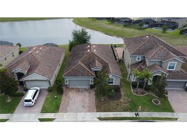 An aerial view of a home with a brick driveway and tile roof near a lake in a residential neighborhood at 2016 Lakeside Ave, Davenport, FL 33837