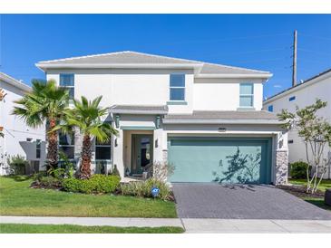 Inviting two-story home with a well-manicured lawn, palm trees, and a driveway with a two-car garage at 2623 Calistoga Ave, Kissimmee, FL 34741