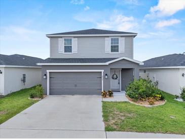 Two-story home with gray siding, white shutters, a two-car garage, and a well-manicured lawn at 3926 Palazzo Pl, Winter Haven, FL 33884