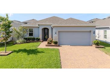 Charming single-story home featuring a brick driveway, well-manicured lawn, and a two-car garage at 1021 Golden Dawn Loop, Minneola, FL 34715