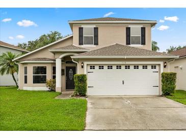 Charming two-story home with a well-manicured lawn and a two-car garage, enhanced by black shutters at 114 Harwood Cir, Kissimmee, FL 34744