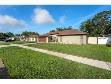 Charming single-story home with a two-car garage, lush lawn and well-maintained landscaping at 12542 Idaho Woods Ln, Orlando, FL 32824