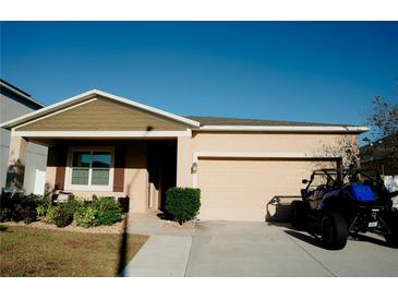 Beige single-story home featuring a 2 car garage, well manicured lawn and landscaping at 153 Taft Dr, Davenport, FL 33837