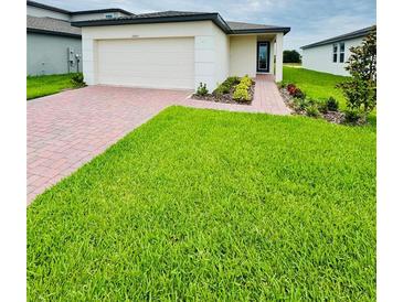 Charming single-story home with a well-manicured lawn and a brick paver walkway leading to the front door at 2505 Merseyside Ct, Haines City, FL 33844