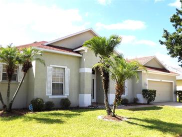 Charming single-story home featuring a well-manicured lawn, a two-car garage, and beautiful palm trees in the front yard at 3074 Bay Laurel N Cir, Kissimmee, FL 34744