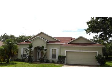 Inviting single-story home featuring a well-maintained lawn, attached two-car garage, and classic architecture at 3074 Bay Laurel N Cir, Kissimmee, FL 34744