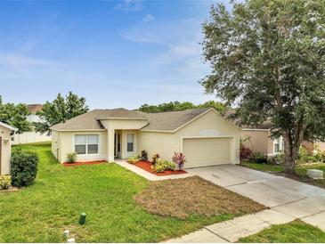 Charming single-story home featuring lush green lawn, mature landscaping, and a two-car garage at 3274 Hunters Chase Loop, Kissimmee, FL 34743