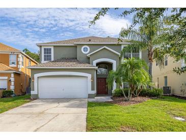 Charming two-story home featuring a two-car garage, arched entry, and lush landscaping at 4697 Golden Beach Ct, Kissimmee, FL 34746