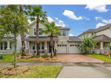 Inviting two-story home featuring a three-car garage, front porch, and lush landscaping with palm trees at 4952 Creekside Park Ave, Orlando, FL 32811