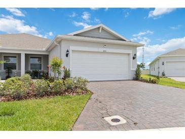 Charming home featuring an attached two car garage, manicured lawn, and a beautiful brick paver driveway at 1895 Spring Shower Cir, Kissimmee, FL 34744