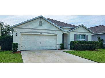 Charming single-story home with a two-car garage, manicured lawn, and neutral color palette at 2479 White Lilly Dr, Kissimmee, FL 34747