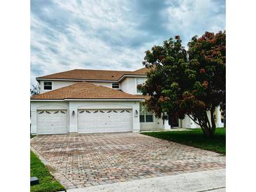 Charming two-story home with a three car garage and a brick driveway with a beautiful lawn and landscaping at 4368 Fox Glen Loop, Kissimmee, FL 34746