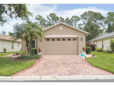 Charming single-story home featuring a brick driveway, lush landscaping, and a welcoming front facade at 516 Millifiora Ln, Kissimmee, FL 34759