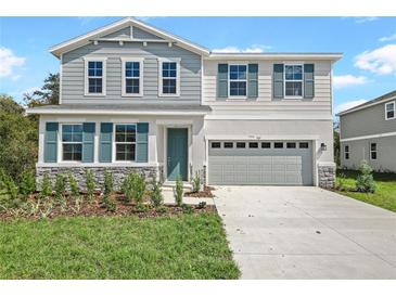 Charming two-story home with light blue and white siding, shutters, stone accents, and a well-manicured lawn at 565 Summit River Dr, Apopka, FL 32712