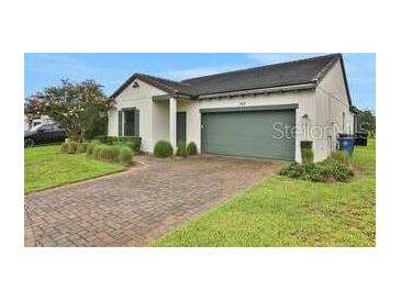 Inviting single-story home with a two-car garage, beautiful lawn and minimalist landscaping at 163 Kenny Blvd, Haines City, FL 33844