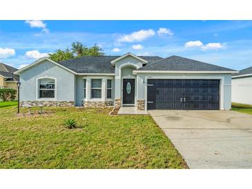 Charming single-story home with a well-maintained lawn, a dark roof, and attached two-car garage at 1913 Manatee Ct, Kissimmee, FL 34759