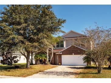 Charming two-story home with a brick facade and a well-manicured front yard and beautiful, mature trees at 2703 Eagle Canyon S Dr, Kissimmee, FL 34746