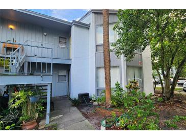 Two-story condo building with gray paint, a small balcony, and trees surrounding the front at 4341 Aqua Vista Dr # A, Orlando, FL 32839
