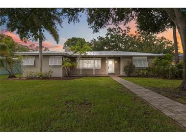 Charming single-story home featuring a metal roof, lush landscaping, and a welcoming walkway at 612 Lakeshore Blvd, Kissimmee, FL 34744