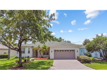 Charming single-story home with a well-manicured lawn, a brick driveway, and a two-car garage at 759 Largo Pass, Poinciana, FL 34759