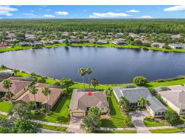 Stunning aerial view of home with lake frontage and lush green landscape; wooded area in the distance at 777 Glendora Road, Poinciana, FL 34759