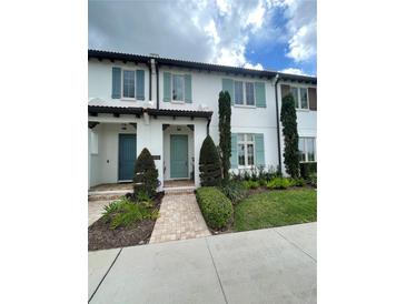 Charming townhome featuring blue shutters and doors, complemented by lush landscaping and a welcoming walkway at 8919 Lakeshore Pointe Dr, Winter Garden, FL 34787