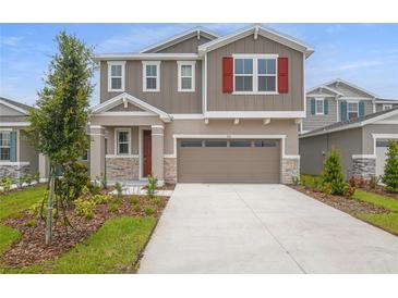 Inviting two-story home with a neutral color scheme, stone accents, and well-manicured landscaping at 216 Flag Lilly Ln, Umatilla, FL 32784