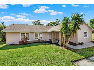 Charming single-story home with lush green lawn and mature palm trees in a sunny setting at 3 Trophy Ln, Kissimmee, FL 34759