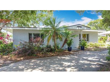 Charming, painted brick home with a well-manicured, partially shaded front yard with palm trees at 301 Oregon Ave, St Cloud, FL 34769