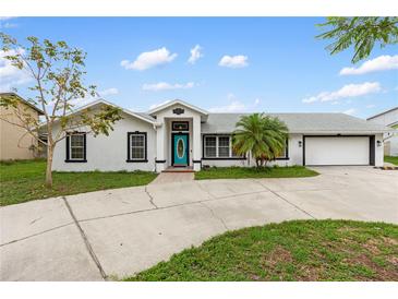 Charming single-story home featuring a teal front door, attached garage, and well-manicured landscaping at 4407 Lake Trudy Dr, St Cloud, FL 34769