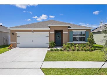 Charming single-story home featuring a well-maintained lawn and a two-car garage on a sunny day at 1102 Tupelo Trl, Haines City, FL 33844