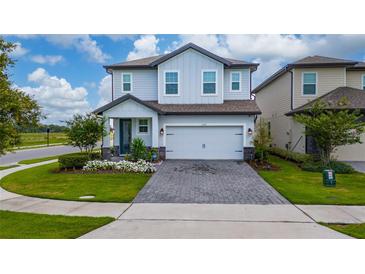 Charming two-story home with manicured lawn, flower beds, and a brick paver driveway at 1335 Greenfield Loop, Kissimmee, FL 34747