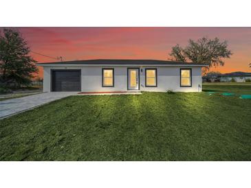 Charming single-story home featuring a modern design, fresh landscaping, and a gray painted garage at 2 Dogwood Radl, Ocala, FL 34472