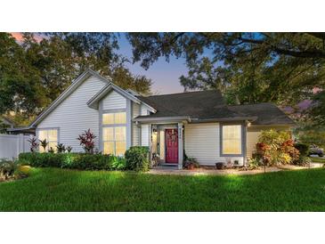 Charming home with lush landscaping, a red door, and large windows creating a welcoming curb appeal at 2225 Maryday Ct, Orlando, FL 32812