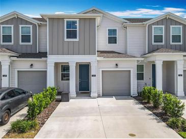 Charming townhome featuring a gray two-car garage, complemented by well-maintained landscaping at 7685 Stone Creek Trl, Kissimmee, FL 34747